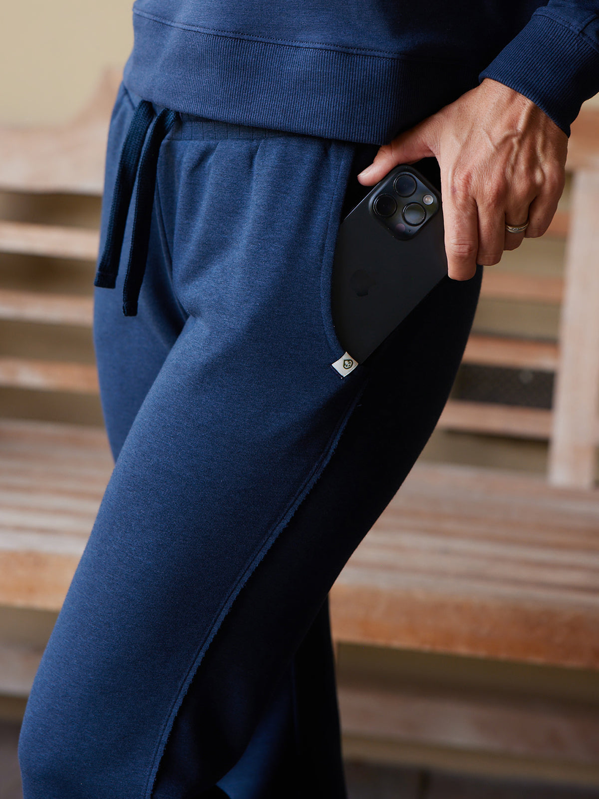Navy blue Stadium French Terry wide leg sweatpant with drawstring waist and side pocket holding a black smartphone tasc Performance Stadium French Terry Wide Leg Pant (ClassicNavy)