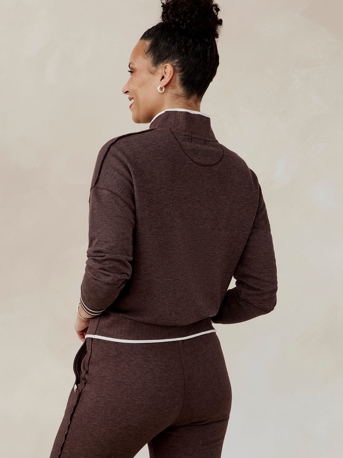 Woman wearing a dark brown French terry half zip sweatshirt with white trim on collar, cuffs, and waistband, back view tasc Stadium French Terry Half Zip (MochaHeather)