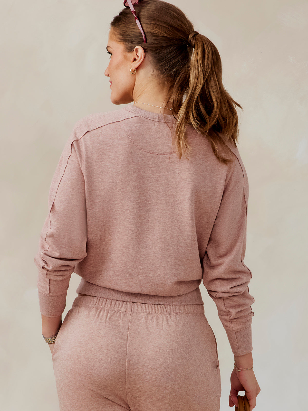Woman wearing dusty rose Stadium French Terry sweatshirt and matching pants, back view with long sleeves and ribbed cuffs tasc Stadium Sweatshirt (AntiqueRosyHeather)