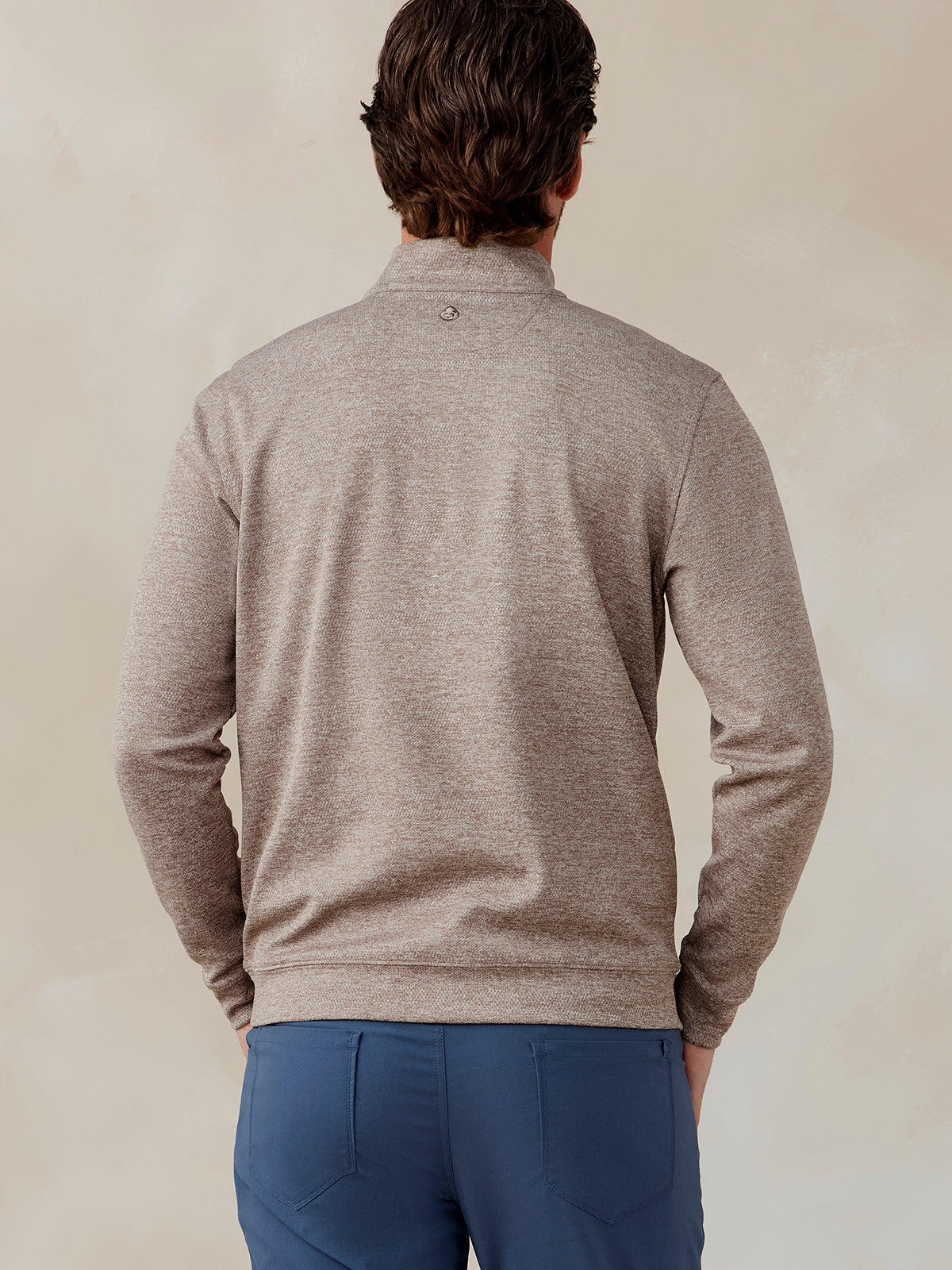 Man wearing a light brown Crest Jacquard quarter zip pullover shown from the back with blue pants tasc Crest Jacquard Quarter Zip (Tan)