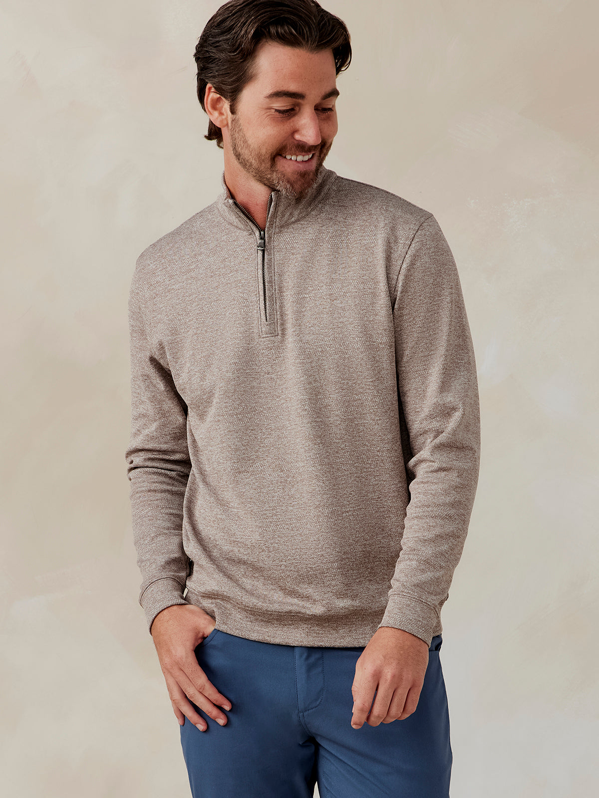 Man wearing a beige Crest Jacquard quarter zip pullover with long sleeves and a front zipper, paired with blue pants tasc Crest Jacquard Quarter Zip (Tan)