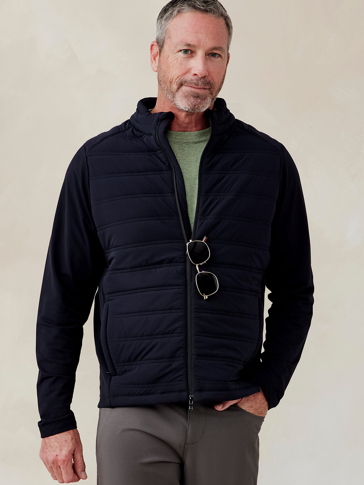 Man wearing a black Hilltop Hybrid Jacket with quilted front panels, zip closure, and side pockets over a green shirt Hilltop Hybrid Jacket (Black)