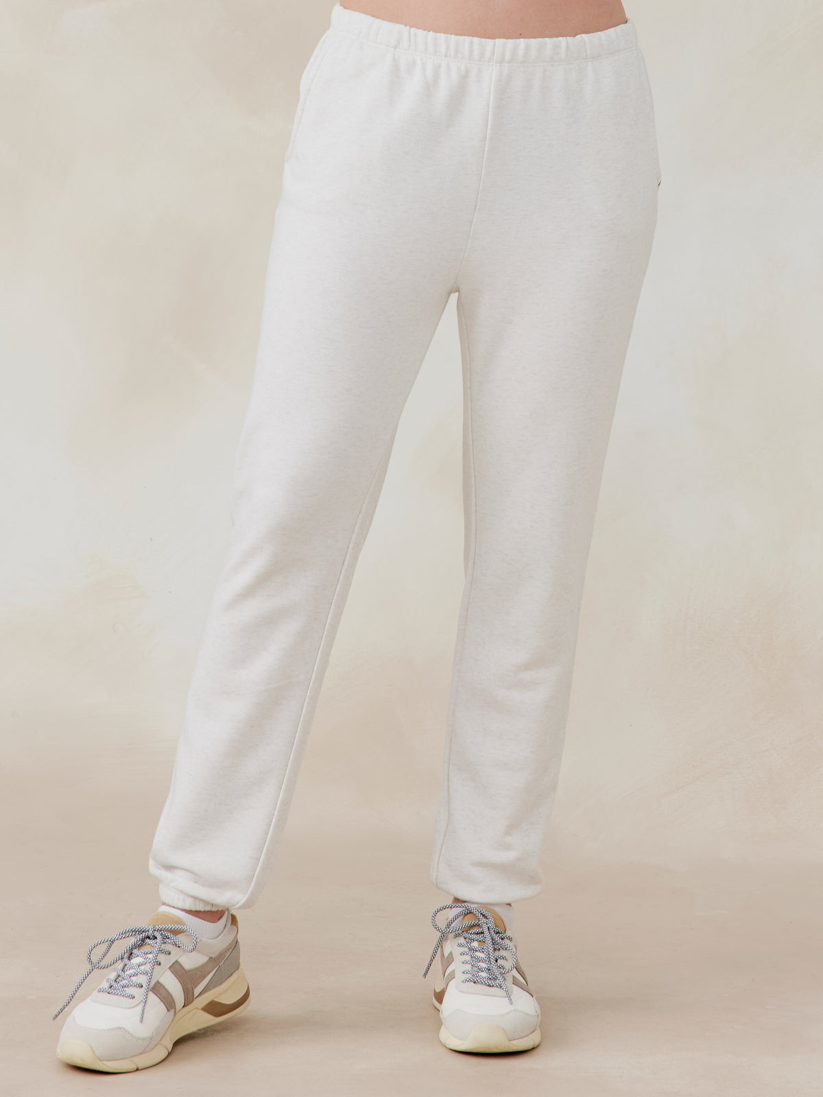 Off-white Stadium French Terry sweatpants with elastic waistband and cuffs, worn by model with sneakers, front view tasc performance stadium sweatpant (CoconutHeather)