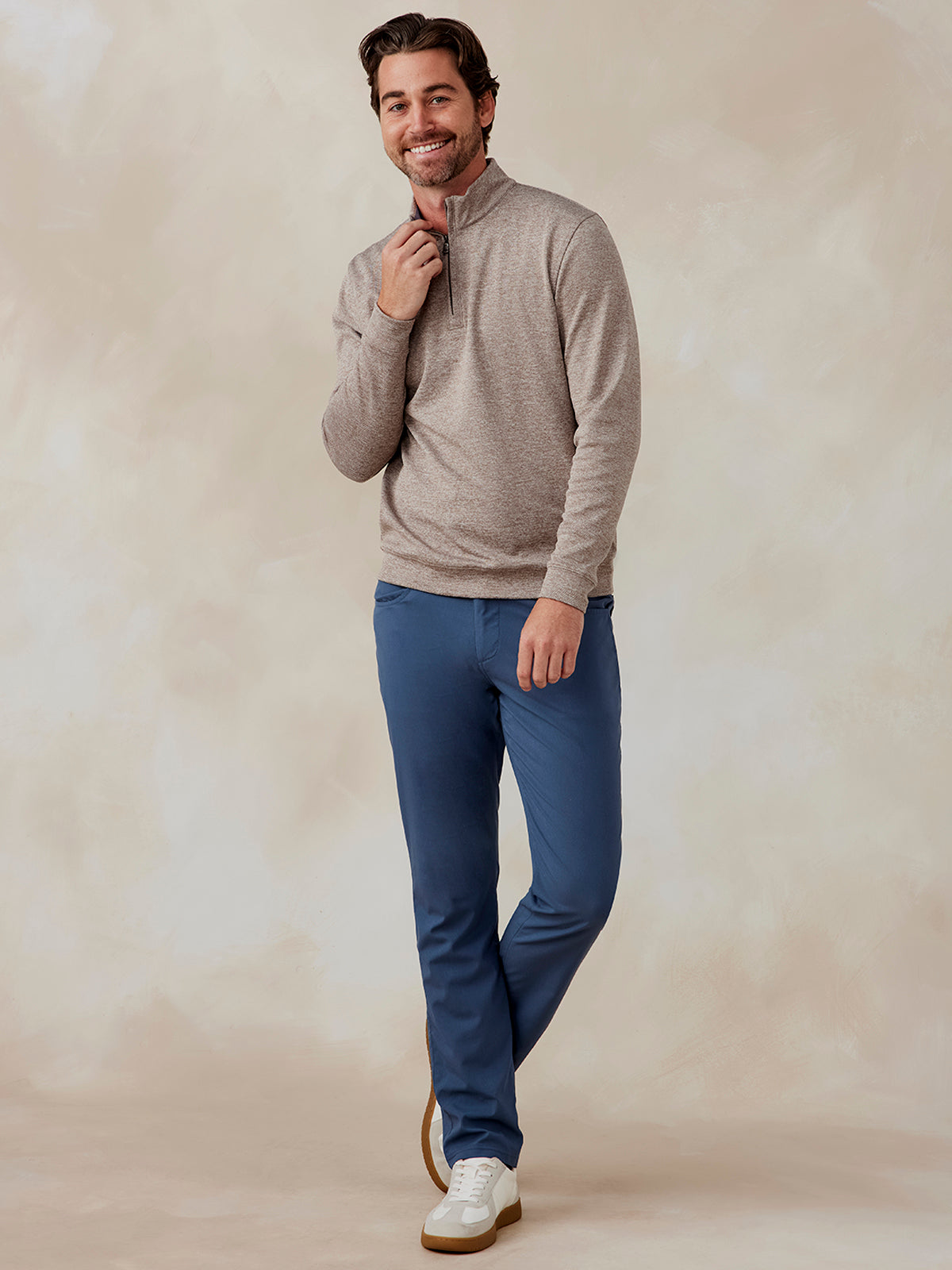 Man wearing beige Crest Jacquard quarter zip pullover with stand collar and blue pants, front view, smiling tasc Crest Jacquard Quarter Zip (Tan)