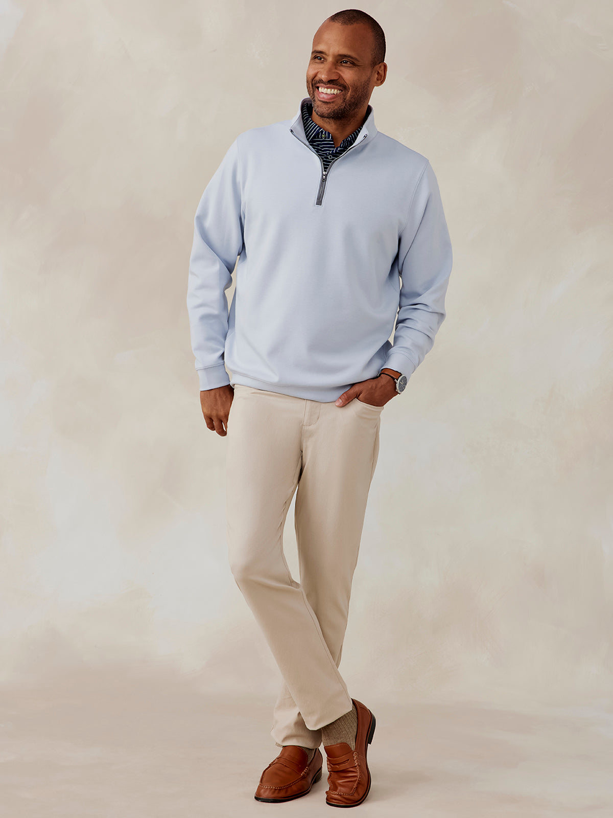 Man wearing light blue Highlands quarter zip pullover with beige pants and brown loafers, standing against neutral background tasc Highlands Quarter Zip (Cloud)
