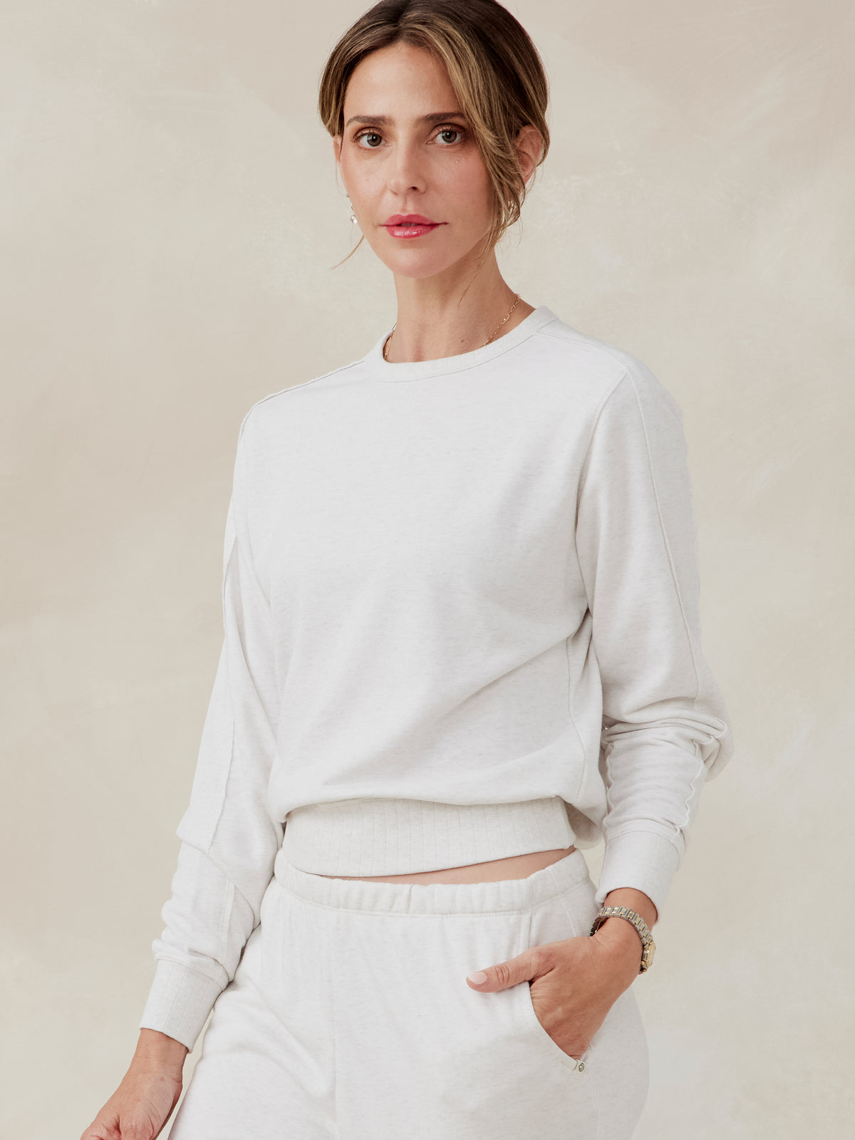 Woman wearing an off-white French terry sweatshirt with ribbed cuffs and waistband, paired with matching pants, front view tasc Stadium Sweatshirt (CoconutHeather)